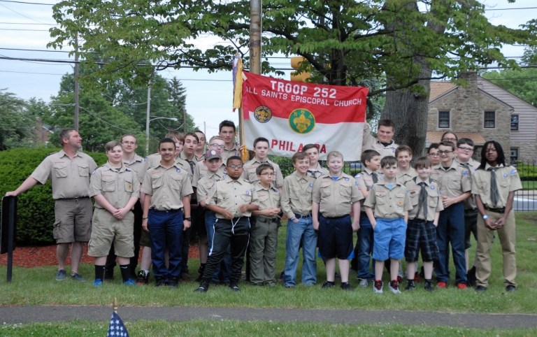 group of boy scouts and leaders around troop flag